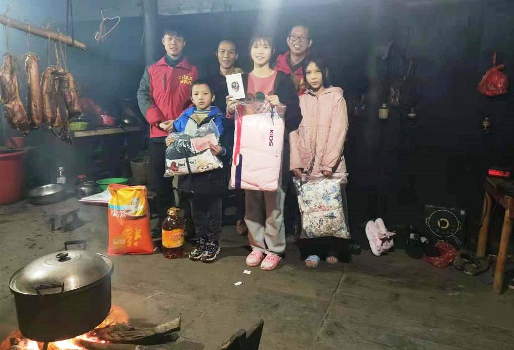 广西三江良冲村第一书记卓远华（右二）受皇岗边检站民警委托为脱贫户送上慰问品并合影留念。.png