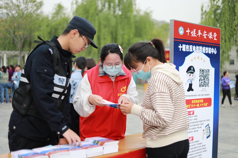 在十堰市郧阳区白浪镇文明实践活动现场，志愿者向群众宣讲反电诈知识.jpg