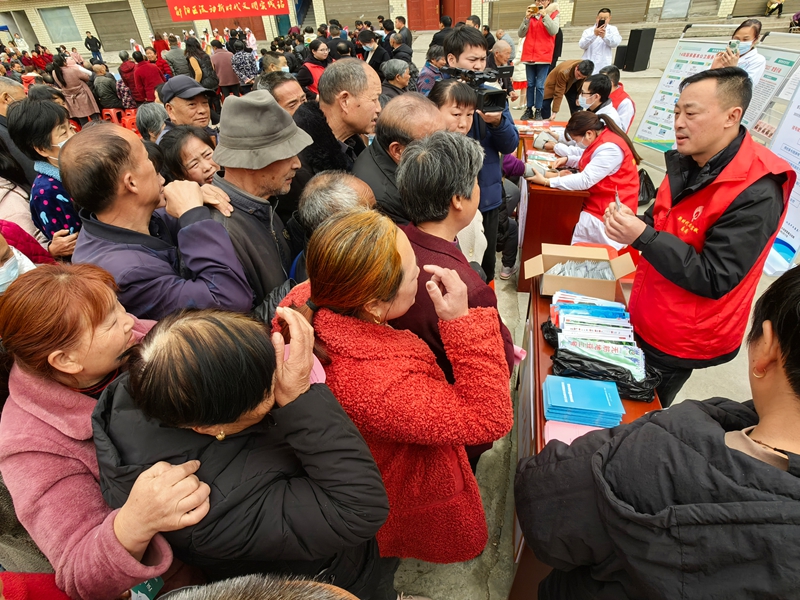 在十堰市郧阳区胡家营镇文明实践活动现场，志愿者向群众介绍科学施肥知识，并发放农资.jpg