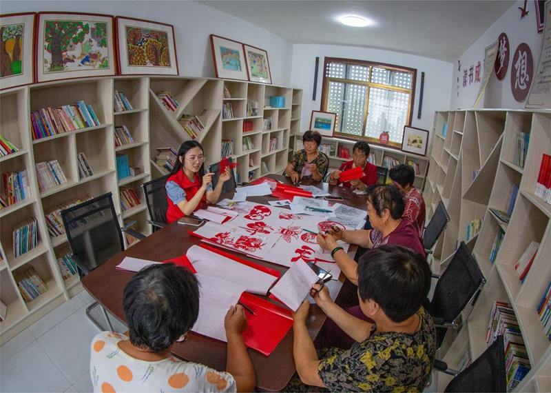 山东德州乐陵市非遗传承志愿者深入基层村社，向群众传授剪纸技艺.jpg