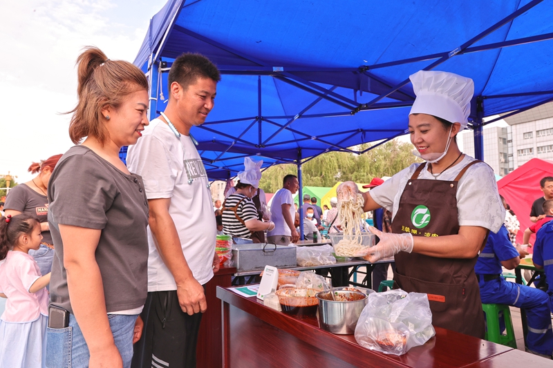 在新疆生产建设兵团第六师五家渠市第二十届郁金香文化旅游节现场，非遗美食展区内，游客正在购买芳草湖凉皮子。 李华北 摄.jpg