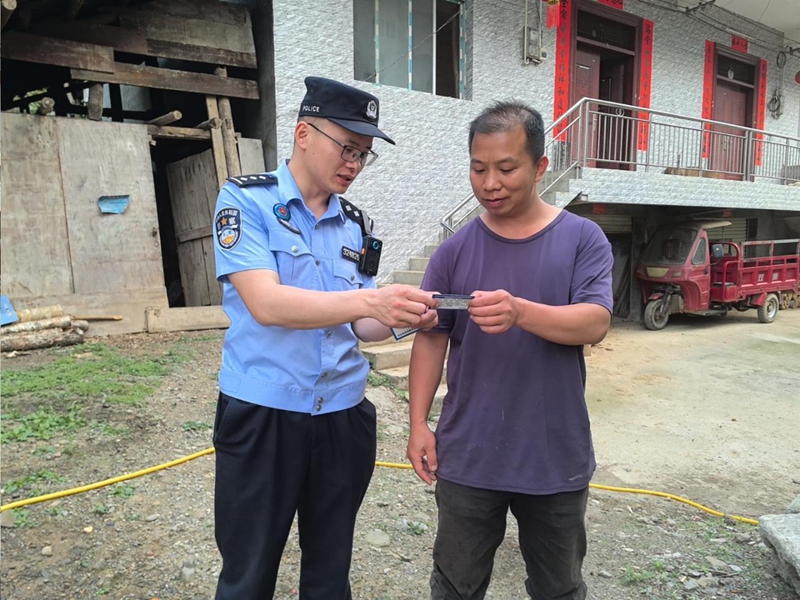 图为黄明忠向辖区群众发放警民联系卡（蒋德校 摄）.jpg